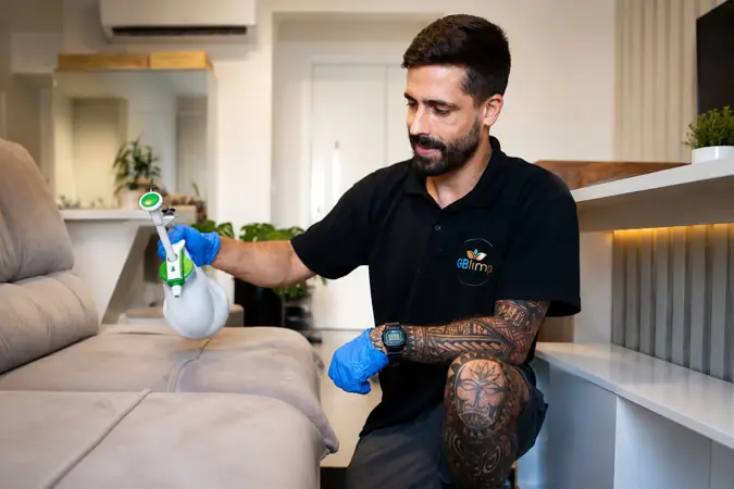 Profissional da GBlimp higienizando um sofá claro em sala de estar